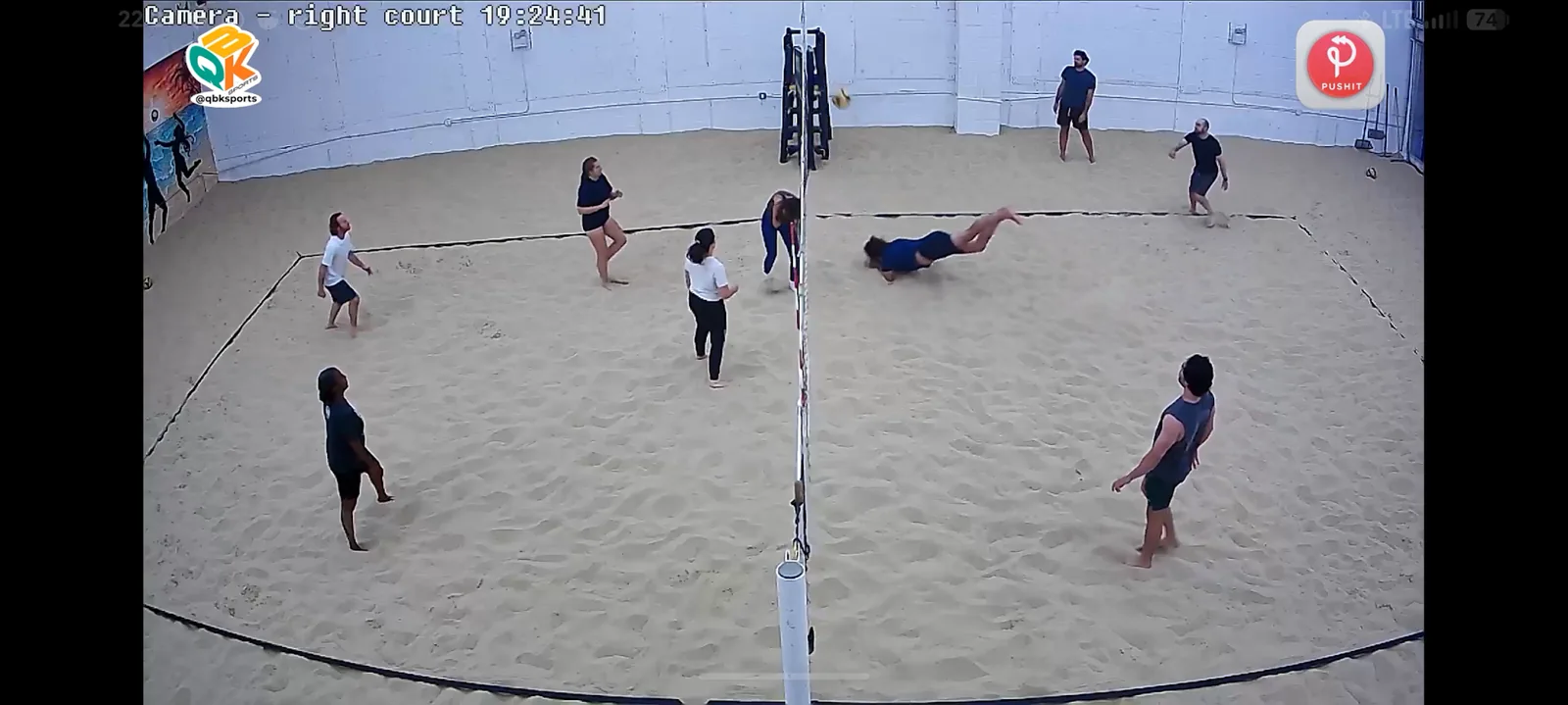 A player diving for a volleyball on an indoor sand court